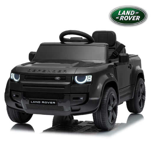 A matte black Land Rover Defender kids' ride-on toy car with a matchiBlack Land Rover Defender 110 12V kids ride-on carng black steering wheel and black wheels, shown on a white background with a reflection and a Land Rover logo badge in the top right corner.
