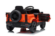 Rear and underside view of orange Land Rover Defender 110 ride-on car